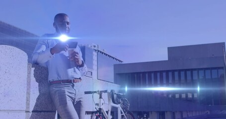 Animation of light spots over african american man using smartphone