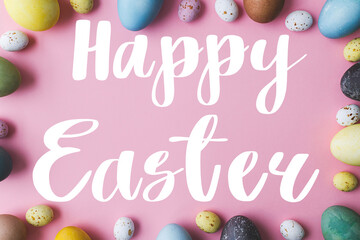 Happy Easter greeting card. Happy Easter text and modern stylish eggs flat lay on pink background. Seasons greeting card, handwritten lettering