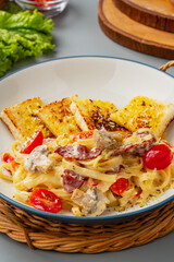 homemade fettuccine pasta with white cream sauce and garlic bread. fettuccine Carbonara made with eggs, hard cheese, cured pork, and black pepper. Italian food.