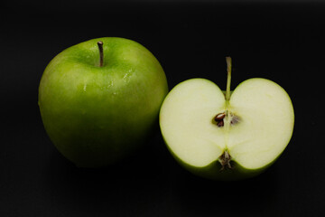 Fresh green apple and sliced isolated on black background.