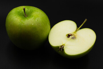 Fresh green apple and sliced isolated on black background.