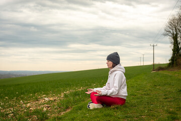  Woman sitting in lotus pose doing yoga outdoors