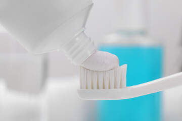 Fototapeta na wymiar Squeezing paste onto toothbrush against blurred background, closeup