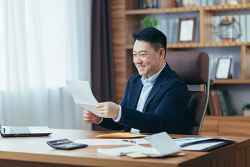 Young Asian man, businessman, satisfied director holding documents, letter, report, received good...