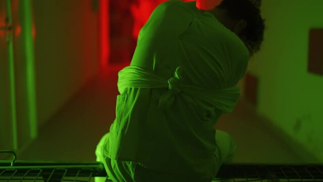 A mad male patient in straitjacket is going crazy in a mental hospital. Mentally ill man with psychic disorders and bipolar disease. Concept of paranoia or schizophrenia and madness or depression.