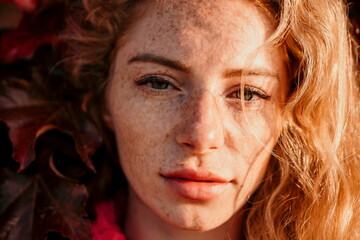 Close up shot of beautiful young caucasian woman with curly blond hair and freckles looking at...