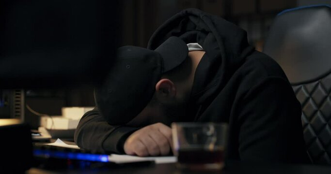 Young programmer sleeps on desk in front of computer at night, man fell asleep during night shift, hacking internet, programming website, tired work guy.