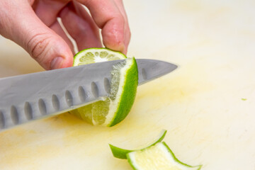 The chef cuts the skin from the lime with a knife on a white board
