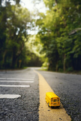 Yellow school bus toy model on country road,view through the forest..Transportation, Children educational and Back to school concept background.