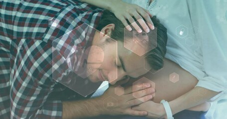 Animation of medical icons over happy caucasian man embracing pregnant wife