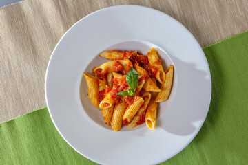 Serving of spicy savory italian penne pasta garnished with fresh basil