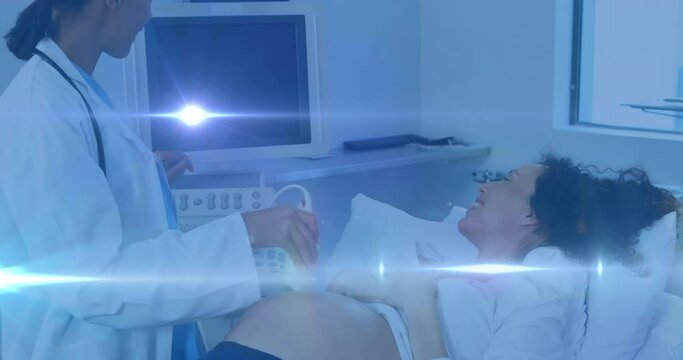 Animation of light spots over happy biracial pregnant woman with doctor