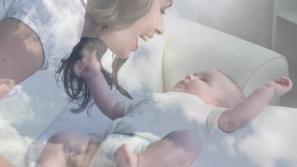 Animation of clouds over happy caucasian mother kissing her baby