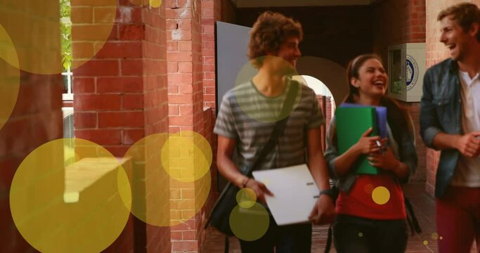 Animation of yellow circles floating over caucasian female and male teenagers on school corridor