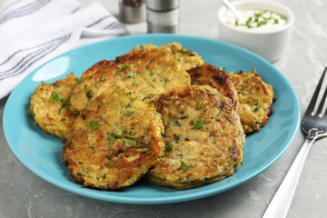 Delicious zucchini pancakes served on grey table, closeup