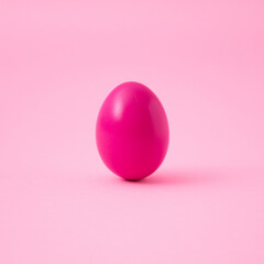 Neon pink egg front view on pastel pink background.