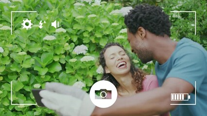 Animation of camera interface over happy biracial couple gardening