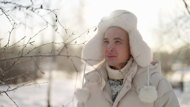 walk in nature in january cold day, handsome smiling man is exploring winter forest in sunny weather