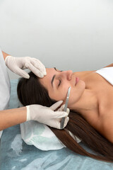 young woman in a beauty center performing a beauty treatment for the skin of the face with the dermaplaning technique
