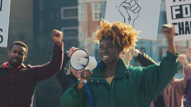 Group of protestors with megaphone holding placards and chanting slogans on demonstration march to promote black lives matter anti racist beliefs - shot in slow motion