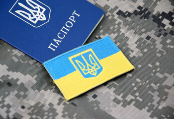 Ukrainian passport and flag with the coat of arms of Ukraine on the background of military...