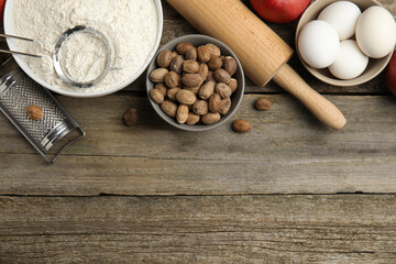 Nutmeg seeds and other ingredients on wooden table, flat lay. Space for text