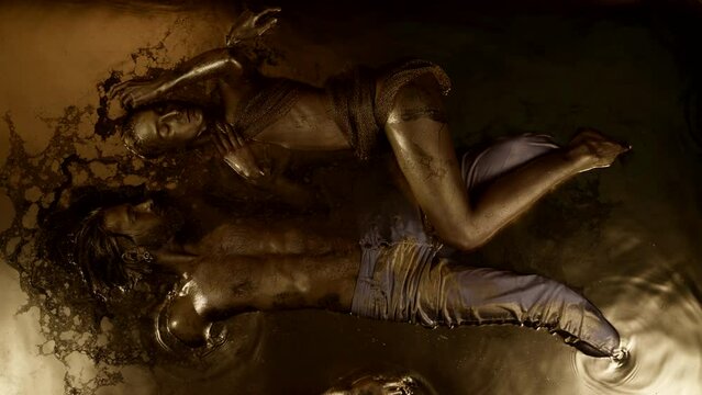 sexy woman and man are lying in golden water of magical pool or lake, top view of sensual figure