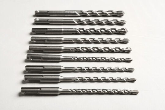 Many different drill bits on white table