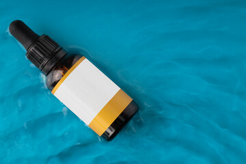 Amber cosmetic bottle on water surface. Summer water pool fresh concept. Flat lay, top view. MOCKUP, copy space.