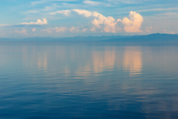 White clouds on Lake Baikal. The clouds are reflected in the water. Evening landscape