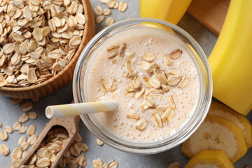 Glass of tasty banana smoothie with oatmeal on light grey table, flat lay
