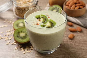 Glass of tasty kiwi smoothie with oatmeal on wooden table