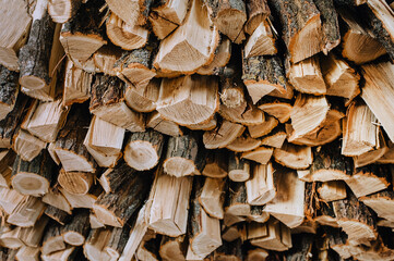 A lot of logs chopped with an ax, dry firewood of acacia, spruce stacked in a row close-up.