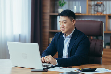 Young handsome asian man, businessman, lawyer, director talking on a video call from a laptop in the office, holds a meeting, consultation, discussion