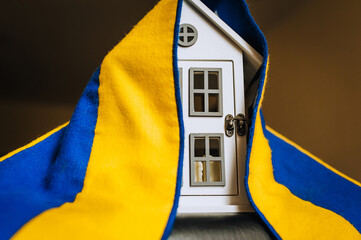 Ukrainian house with national yellow-blue flag. Shelter for homeless refugees from Ukraine to...