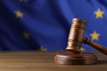 Judge's gavel on wooden table against European Union flag. Space for text