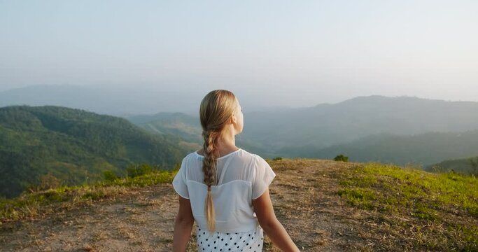 Rear view of young woman in nature walking in mountain and hug herself. Traveling in Asia, vacation trip. Slow motion video. Freedom, relaxation, single travel. View point in northern Thailand