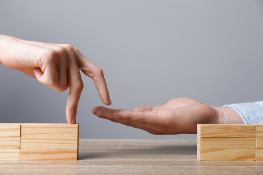 Woman Helping Her Partner To Cross Unfinished Bridge At Wooden Table, Closeup. Connection, Relationships And Deal Concept