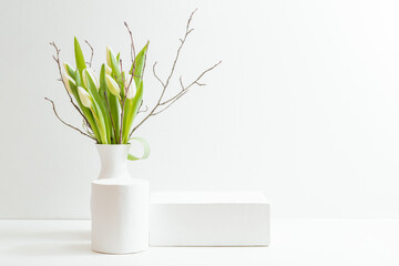 Empty white box and white tulips in a vase on a light background. Mockup banner, podium for display of advertise product