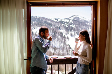 Young couple with cups of hot tea at winter window