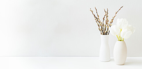 White spring tulips in a vase and willow branch on a white table. Mock up for displaying works