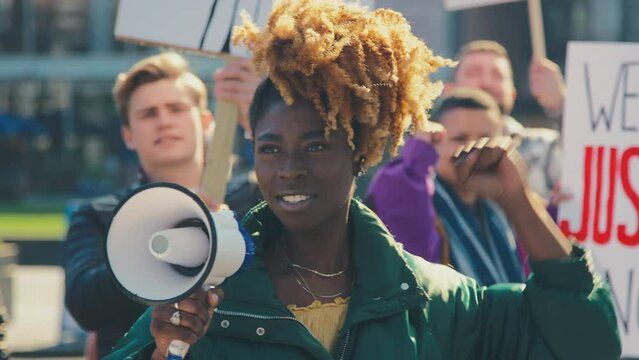 Group of protestors with megaphone holding placards and chanting slogans on demonstration march to promote black lives matter anti racist beliefs - shot in slow motion