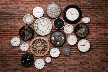 Collection of clocks hanging on red brick wall