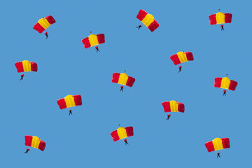 Sports pattern of red-yellow paratroopers gliding against the blue sky.