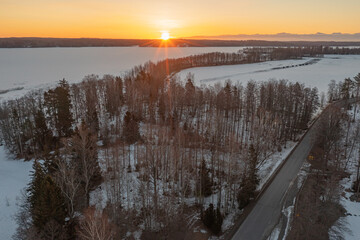 Sunrise over forest and ice-covered lake.Early sunrise in winter. Drone photo. Scandinavia. Finland.
