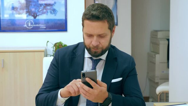 Businessman hold and touching mobile screen writing a message in office