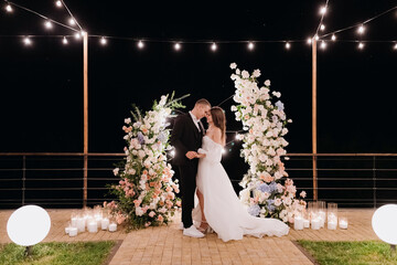 The bride and groom near the arch at the evening ceremony.