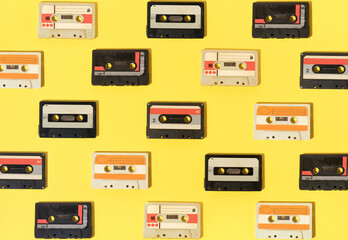 Retro pattern with audio cassettes on yellow background.