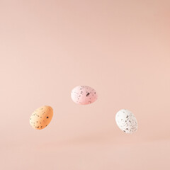 Three Easter eggs in the air on pink background.