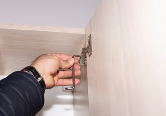  image of handyman assembling kitchen cabinet and screwing door hinge